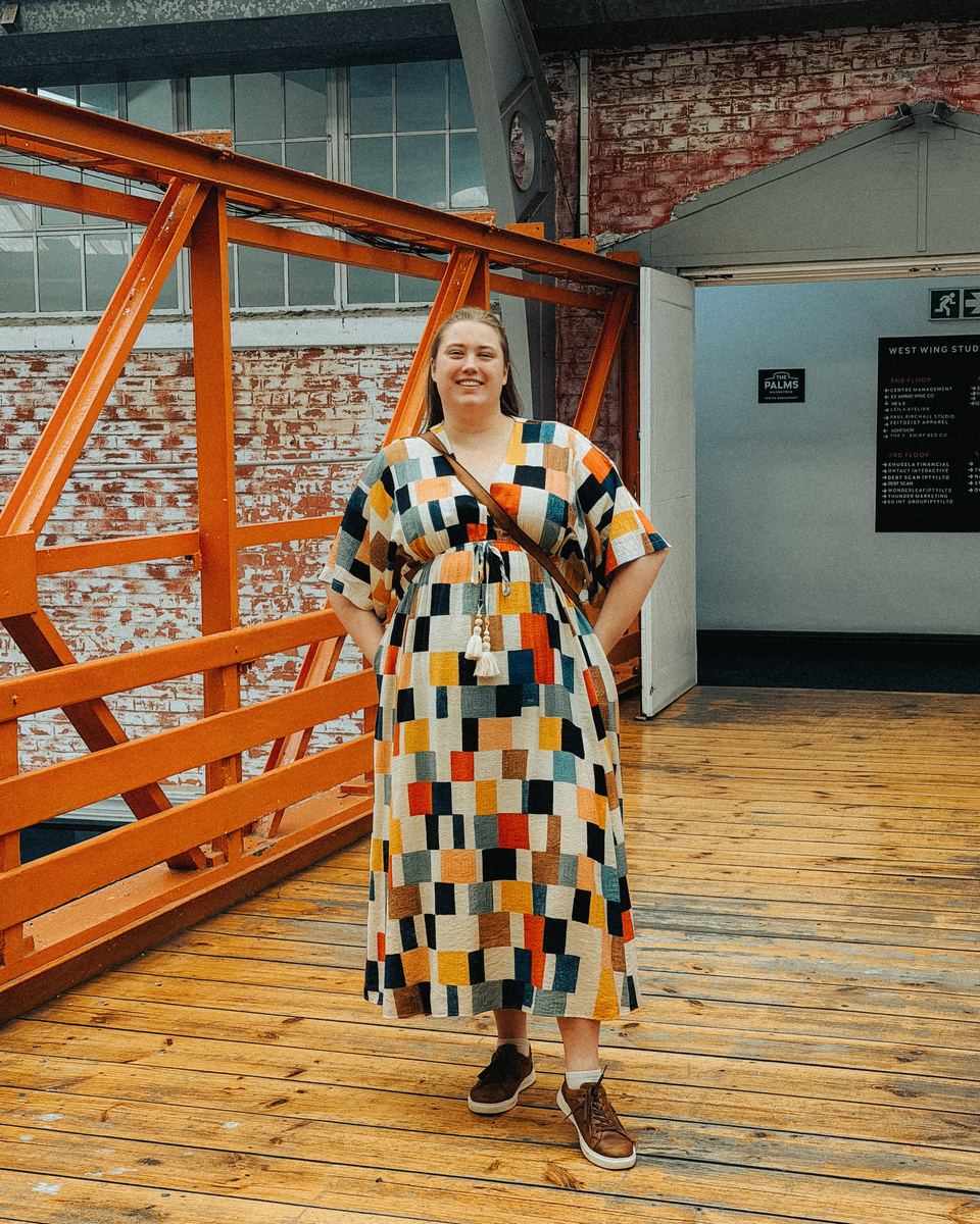 Anke on an orange steel walkway at The Palms in Woodstock, Cape Town, in a colourful patchwork dress