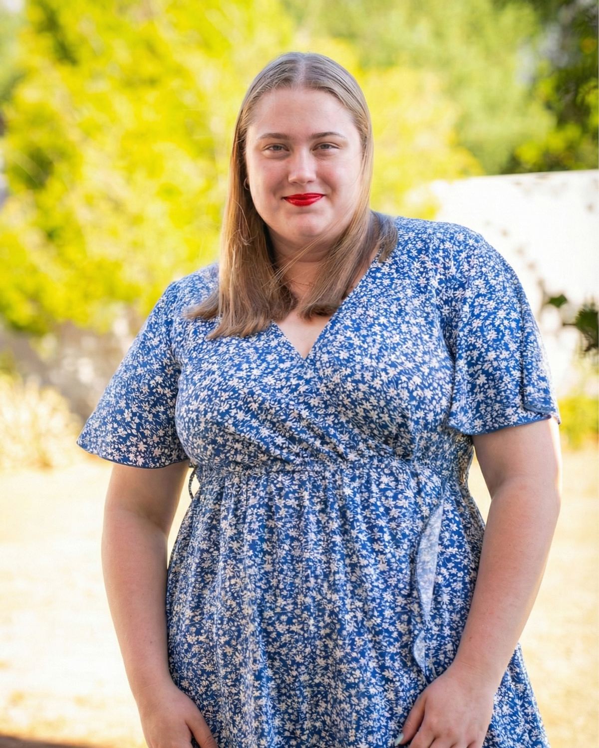 Anke du Randt smiling in a blue floral dress, outdoors in a sunny garden