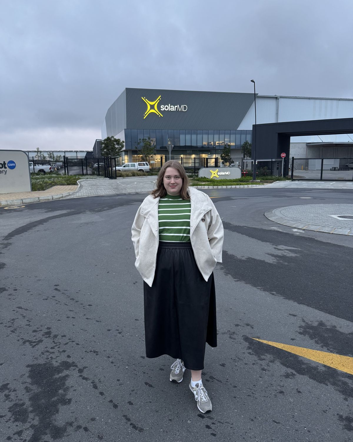 Anke outside the SolarMD building, with the SolarMD logo lit up behind her